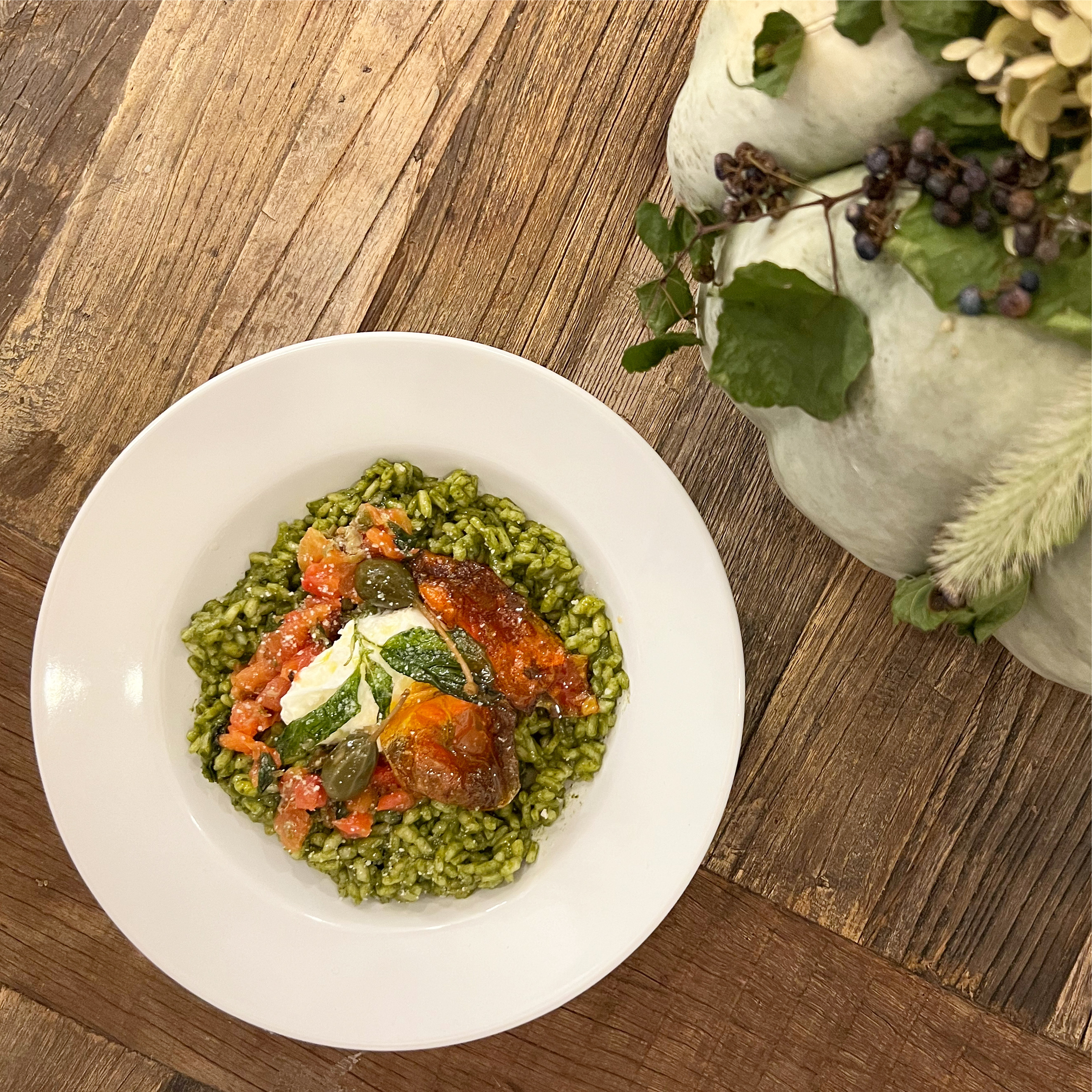 Spinach Risotto topped with Burrata, Tomato Skins, and Caperberries